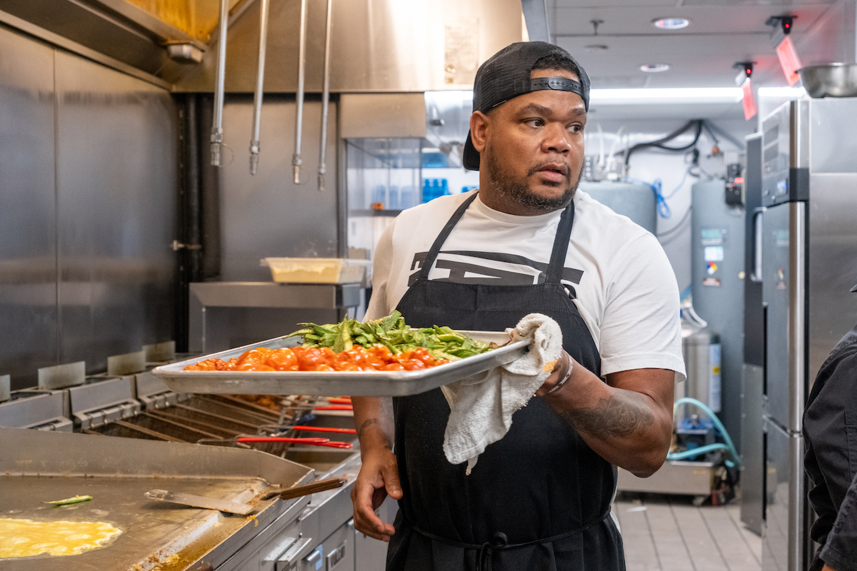 Sammy Davis Jr., chef consultant with Thompson Hospitality, stands in the kitchen at Milk & Honey's SW Wharf location, preparing vegetables for serving. (Ja’Mon Jackson/The Washington Informer)