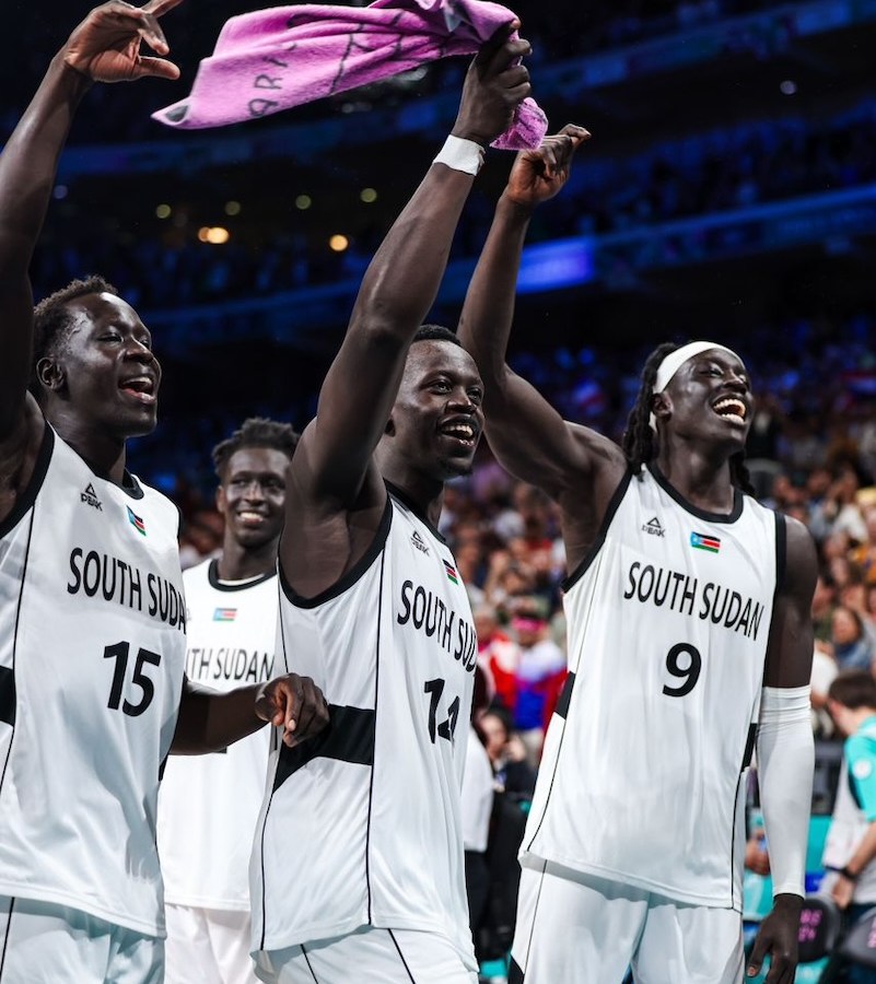 South Sudan’s Bright Stars basketball players — guard Sunday Dech (15), shooting guard Peter Jok (14) and forward/center Wenyan Gabriel forward/center (9) — celebrate their 96-79 win over Puerto Rico during the 2024 Olympic games. (Courtesy of International Basketball Federation)