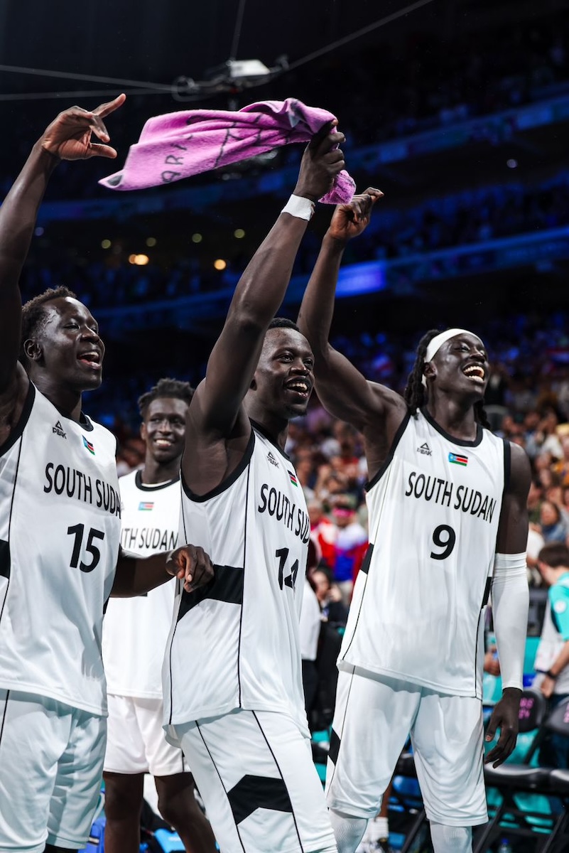South Sudan’s Bright Stars basketball players — guard Sunday Dech (15), shooting guard Peter Jok (14) and forward/center Wenyan Gabriel forward/center (9) — celebrate their 96-79 win over Puerto Rico during the 2024 Olympic games. (Courtesy of International Basketball Federation)