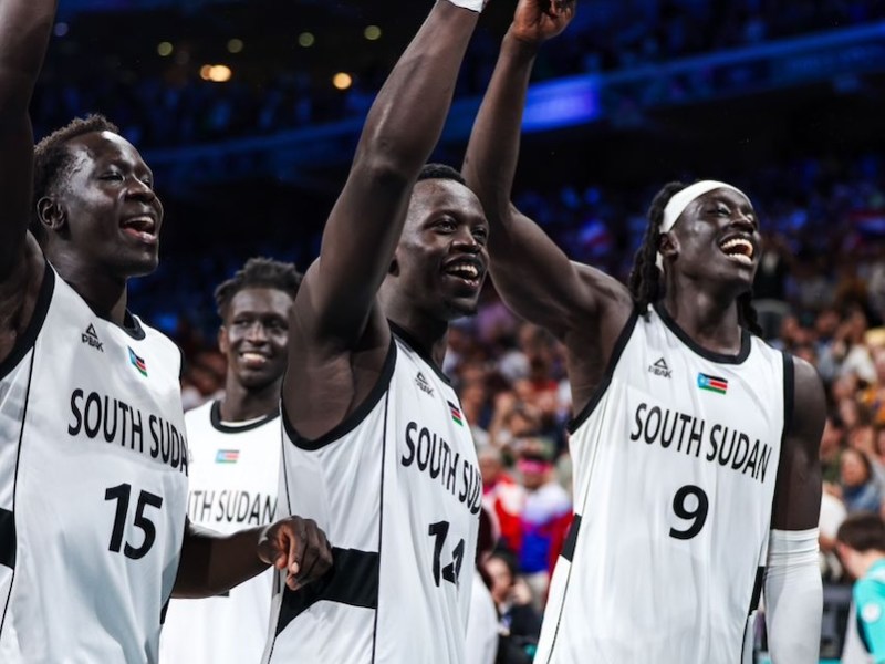 South Sudan’s Bright Stars basketball players — guard Sunday Dech (15), shooting guard Peter Jok (14) and forward/center Wenyan Gabriel forward/center (9) — celebrate their 96-79 win over Puerto Rico during the 2024 Olympic games. (Courtesy of International Basketball Federation)