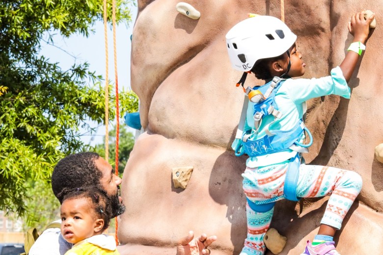 A father encourages his daughter as she participated in rock climbing at the Fight for Children Back To School event. (Skylar Nelson/The Washington Informer)