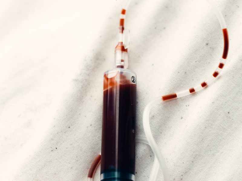 a person holding a syringe filled with blood