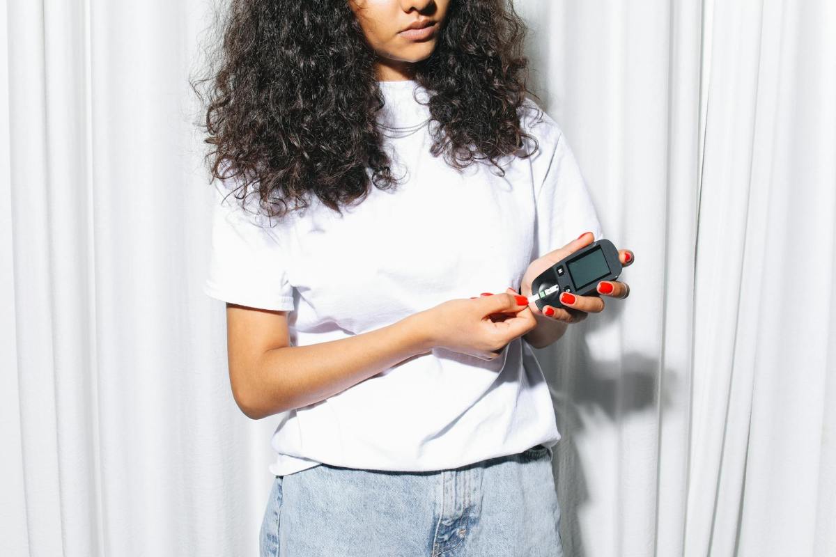 woman in white shirt holding a glucometer